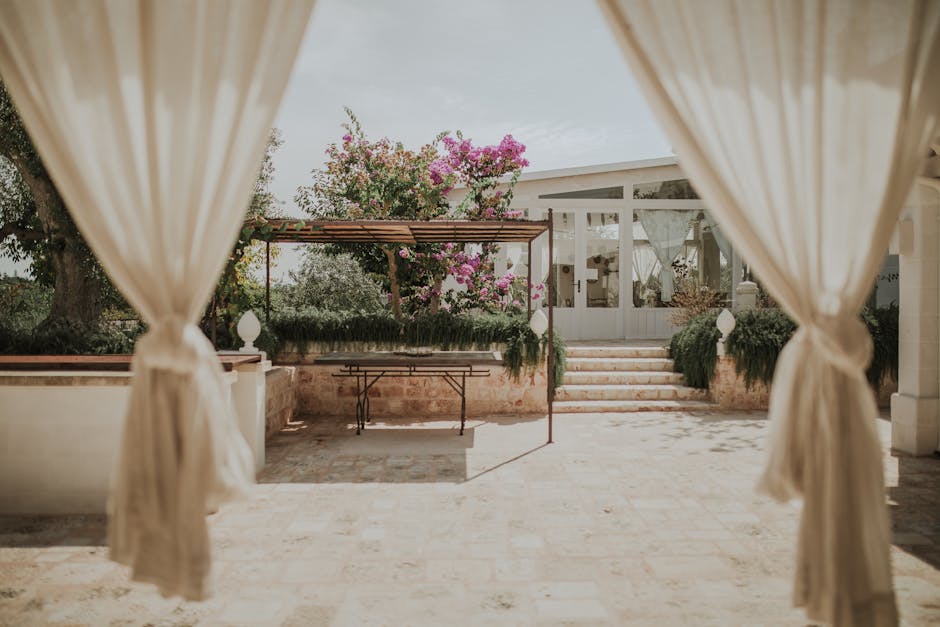 Elegant outdoor gazebo with curtains framing vibrant garden setting.