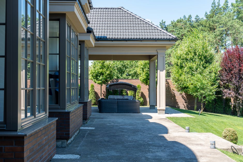 Relaxing patio with modern furniture, garden view, and tiled roof in a summer setting.